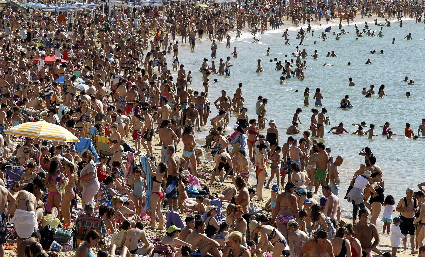 Gran número de personas se han acercado esta tarde a la playa de La Concha de San Sebastián, para aprovechar las altas temperaturas registradas hoy en la ciudad.