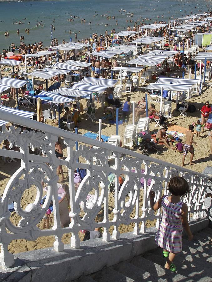 Gran número de personas se han acercado a la playa de La Concha de San Sebastián, para aprovechar las altas temperaturas registradas hoy en la ciudad.