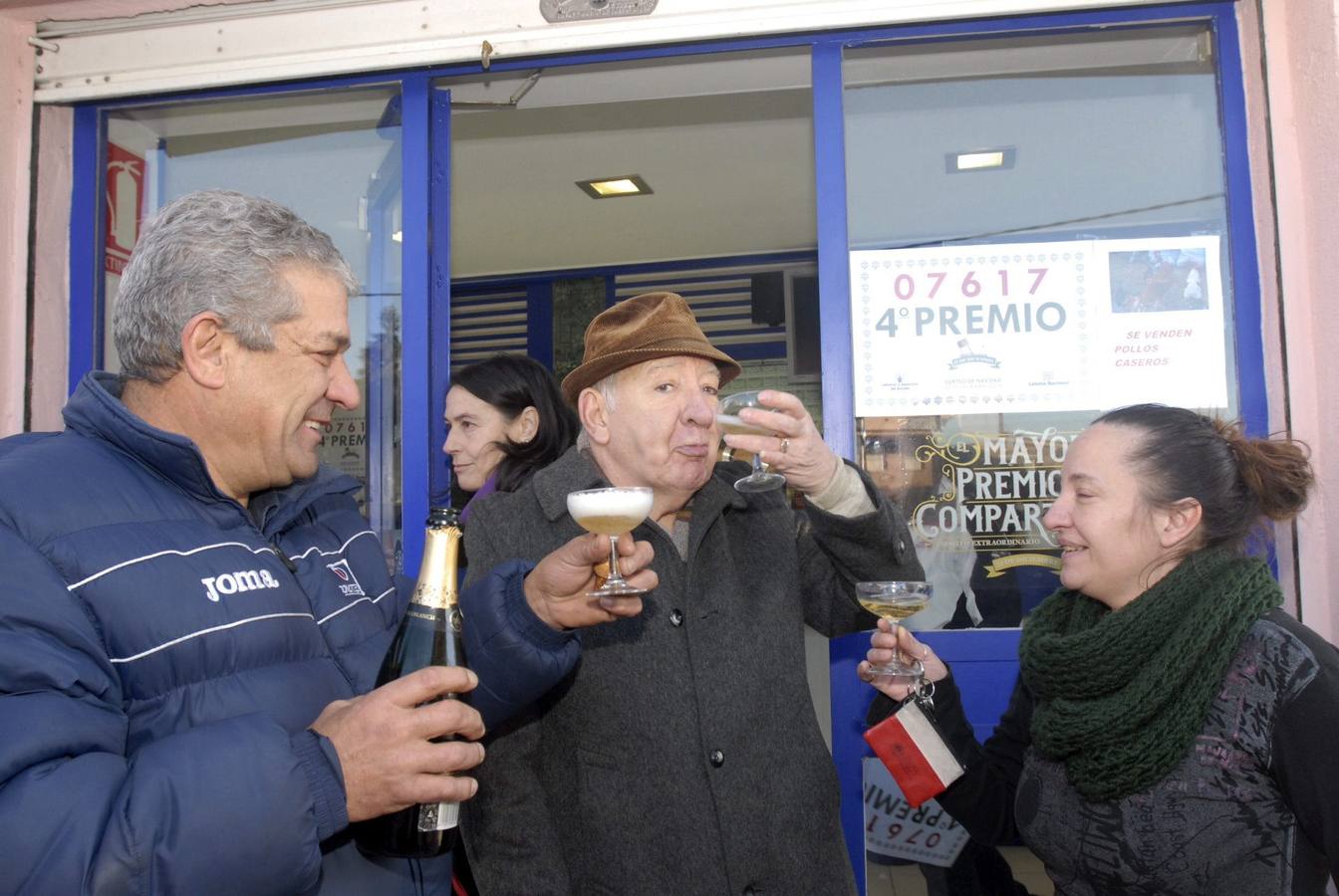 Armunia (León). Loli Martínez (d), hermana de la titular de la administración número 17 ubicada en el número 25 de la calle General Sanjurjo, en Armunia (León), que ha vendido treinta series del 07617, agraciado con uno de los dos cuartos premios dotados con 200.000 euros a la serie (20.000 euros al décimo), y que fueron adquiridas íntegramente por una residencia de ancianos de la localidad, lo celebra con cava en la puerta de su negocio.