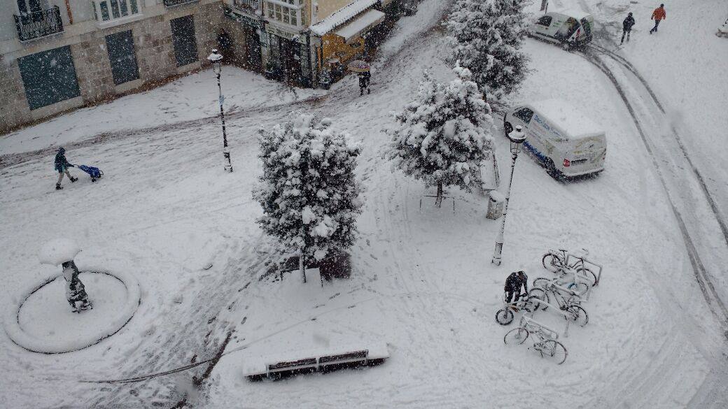 Varias personas caminan por una calle totalmente cubierta de nieve.