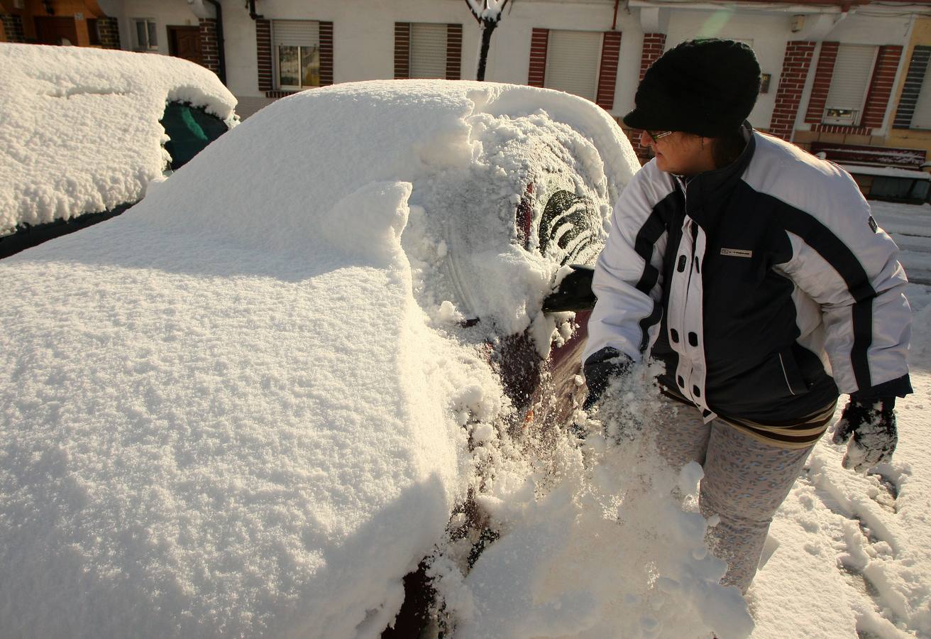 Una mujer quita la nieve acumulada en su coche en la localidad de Toreno (León).