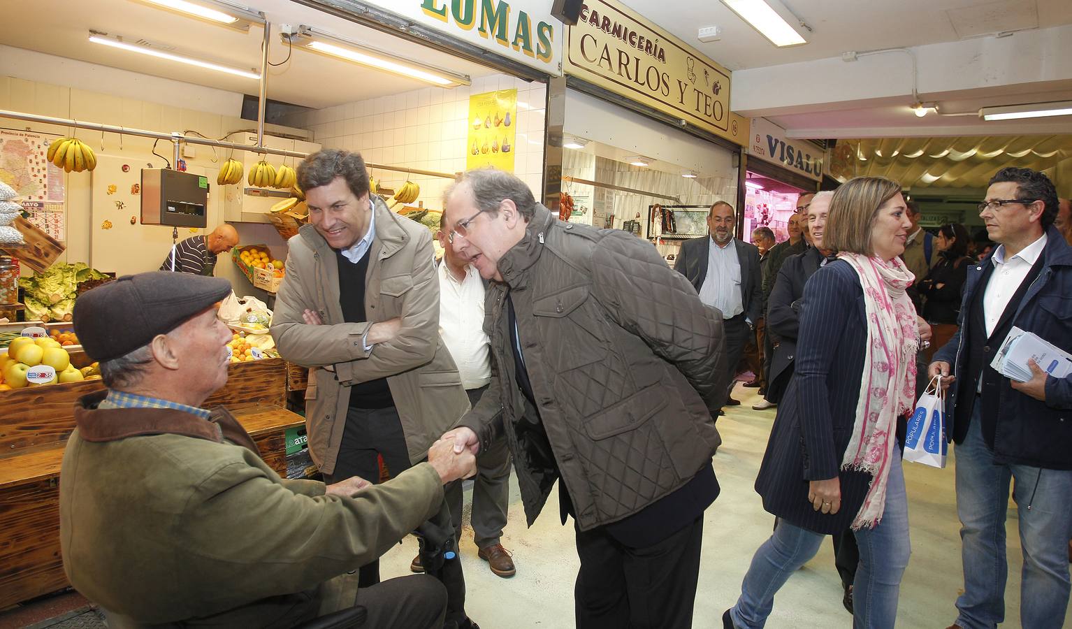 El candidato del PP a la presidencia de la Junta, Juan Vicente Herrera, junto al presidente del PP palentino, Carlos Fernández Carriedo, saludan a un palentino en su visita al mercado.