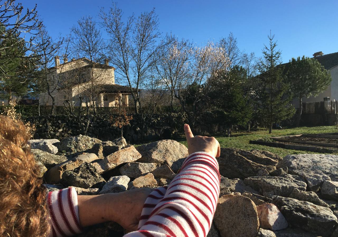 Una mujer muestra árboles en flor en Basardilla (Segovia), a los pies de la Sierra de Guadarrama, que hace un año permanecía totalmente cubierta de nieve y con bajas temperaturas.