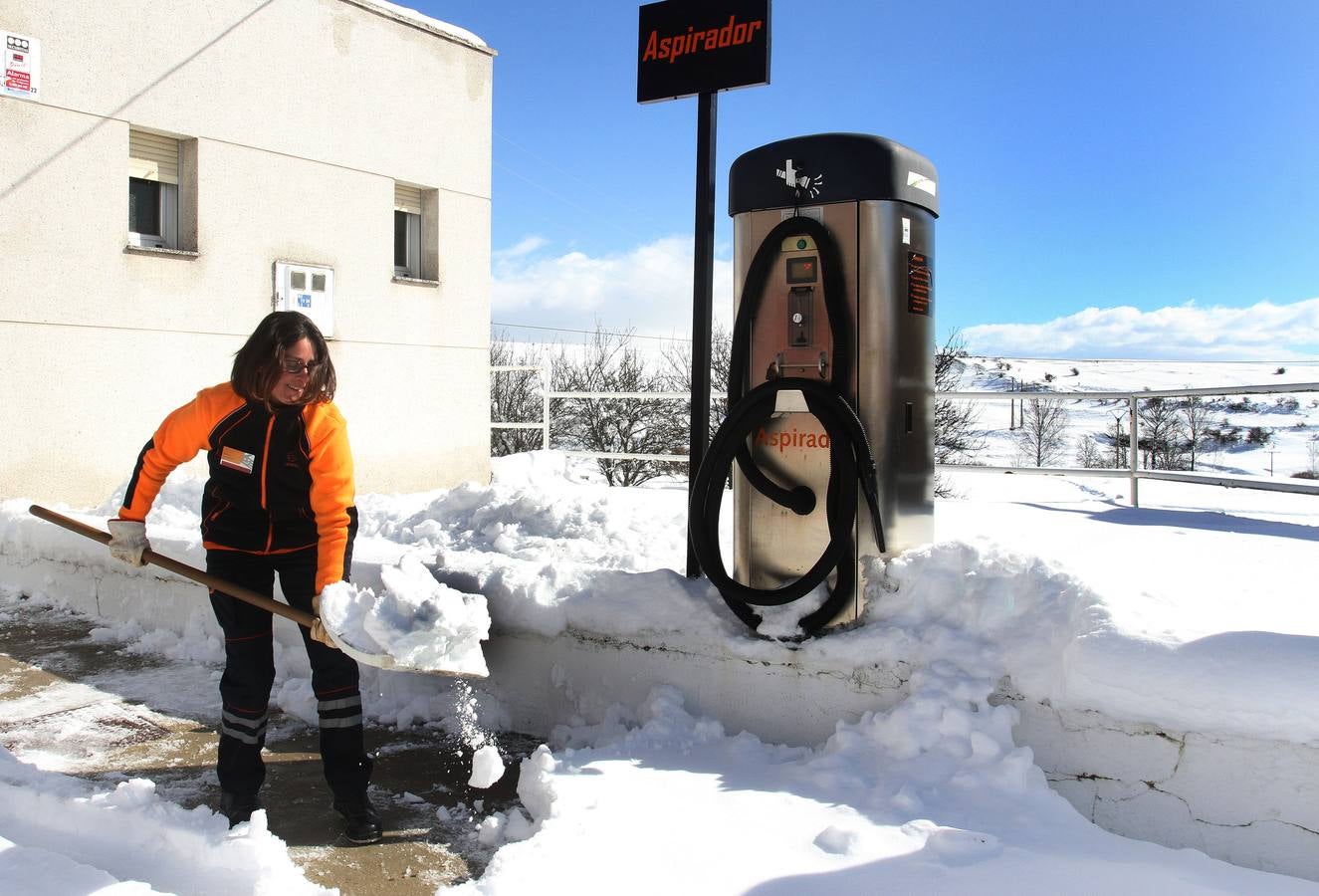 Una operaria de una estación de servicio de Santibañez de la Peña retira la nieve acumulada.