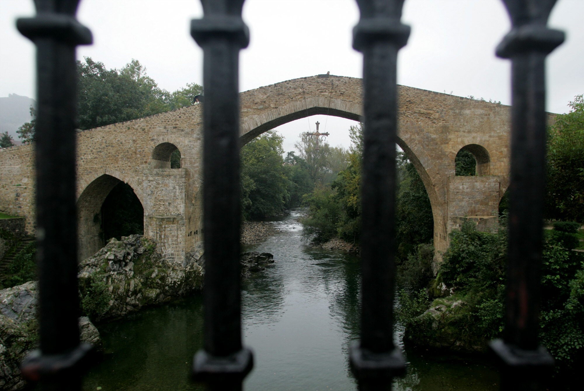 Cangas de Onís (Asturias). Cruza el río Sella y separa los concejos de Cangas de Onís y Parres.Tiene un famoso arco peraltado del que cuelga la Cruz de la Victoria. Seguramente este puente fue levantado sobre uno romano. Hoy es uno de los más espectaculares de España.