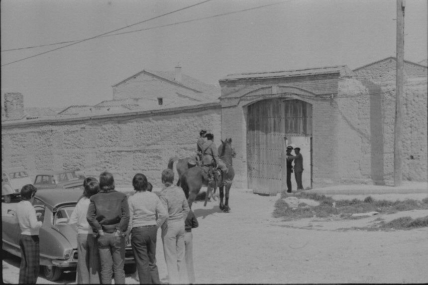 1976. Una pareja de guardias civiles a caballo salen de un corral ante la atentada mirada de algunos participantes.