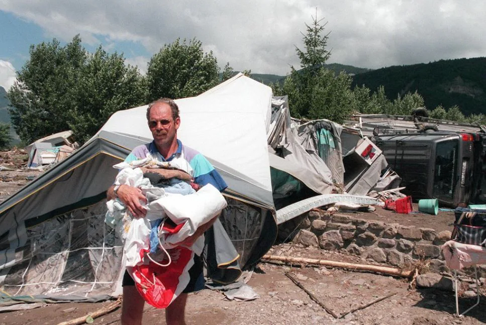 Un hombre recupera sus pertenencias entre las caravanas y tiendas de campaña arrastradas por el agua.