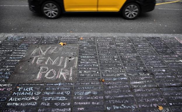 Un taxi pasa junto a los mensajes de apoyo escritos con tiza en una acera de Las Ramblas de Barcelona. 