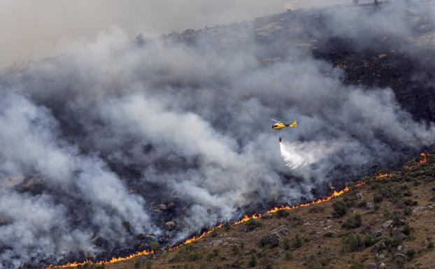 Un helicóptero descarga agua sobre el frente del fuego. 