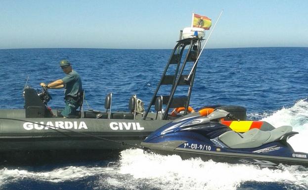 Una embarcación de la Guardia Civil remolca una moto de agua interceptada en el Estrecho.