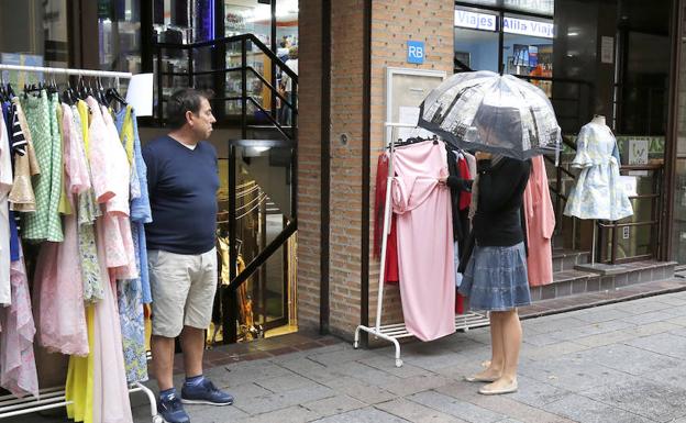 Una viandante con su paraguas observa uno de los expositores colocados en la calle. 