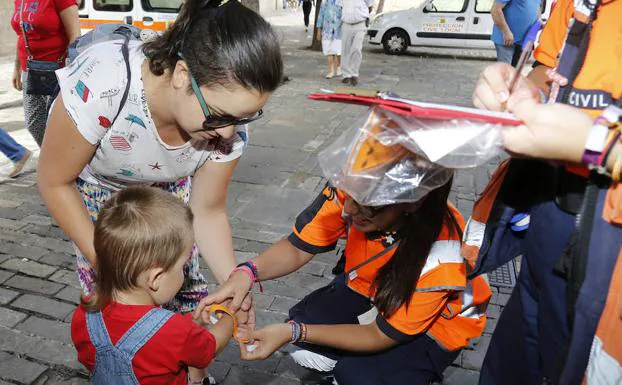 Voluntarios de Protección Civil colocan la pulsera a un niño en la Bocaplaza.