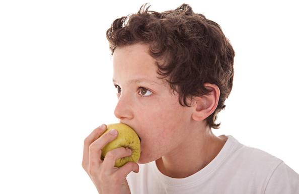 Niño comiendo una manzana.
