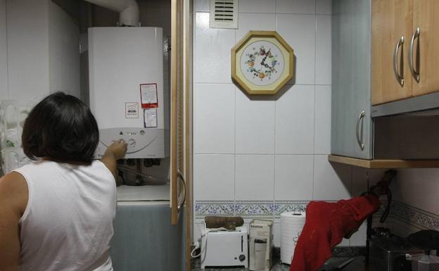 Una mujer manipula su caldera de gas natural en su casa. 