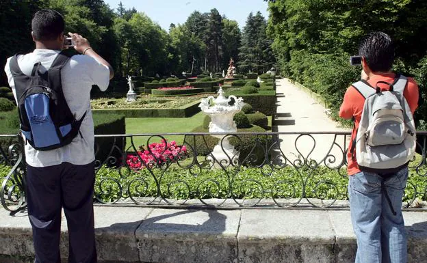 Dos turistas fotografían los jardines del Palacio Real. 