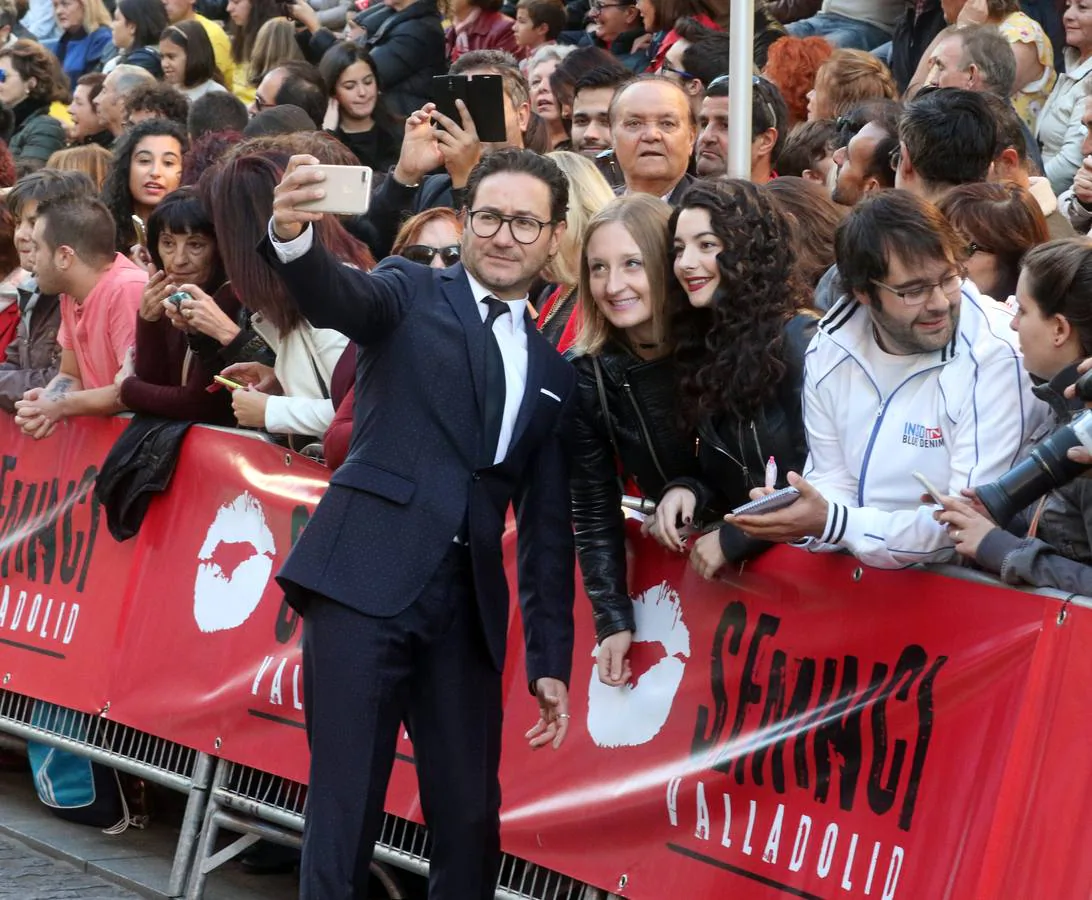 El actor Carlos Santos de hace un selfi con dos jóvenes en la alfombra verde.