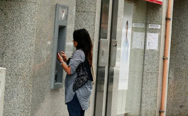 Una mujer utiliza un cajero automático. 