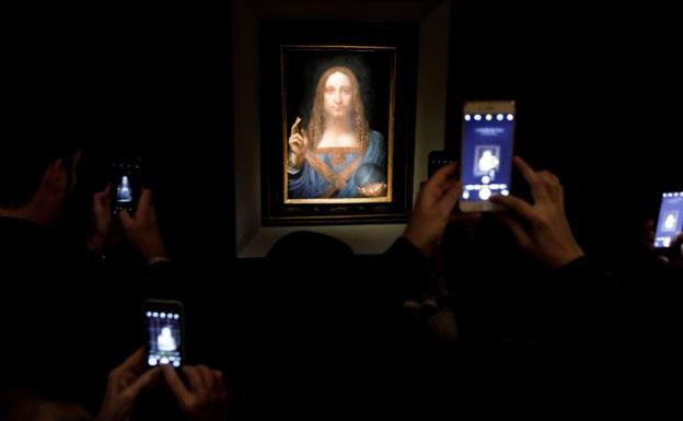 Varias personas fotografían la obra 'Salvator Mundi', de Leonardo da Vinci.
