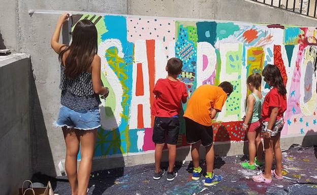 Varios niños elaboran juntos un mural en el parque inclusivo de la localidad vallisoletana de San Pelayo. 