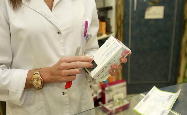 Una farmacéutica muestra un medicamento.