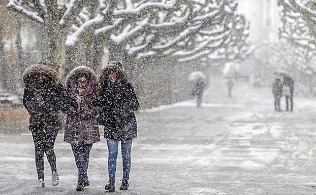 Varias personas caminan por Burgos en medio de una intensa nevada. 