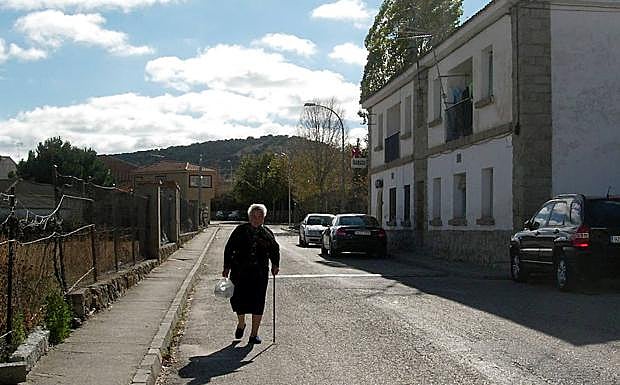 Una mujer pasea por una calle de Zarzuela del Monte. 