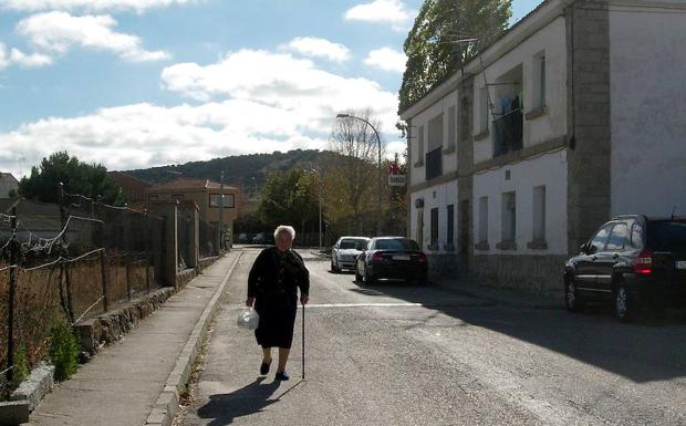 Una mujer pasea por una calle de Zarzuela del Monte. 