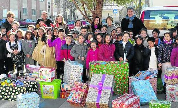 Vecinos de la localidad y representantes municipales posan con los regalos recogidos. 