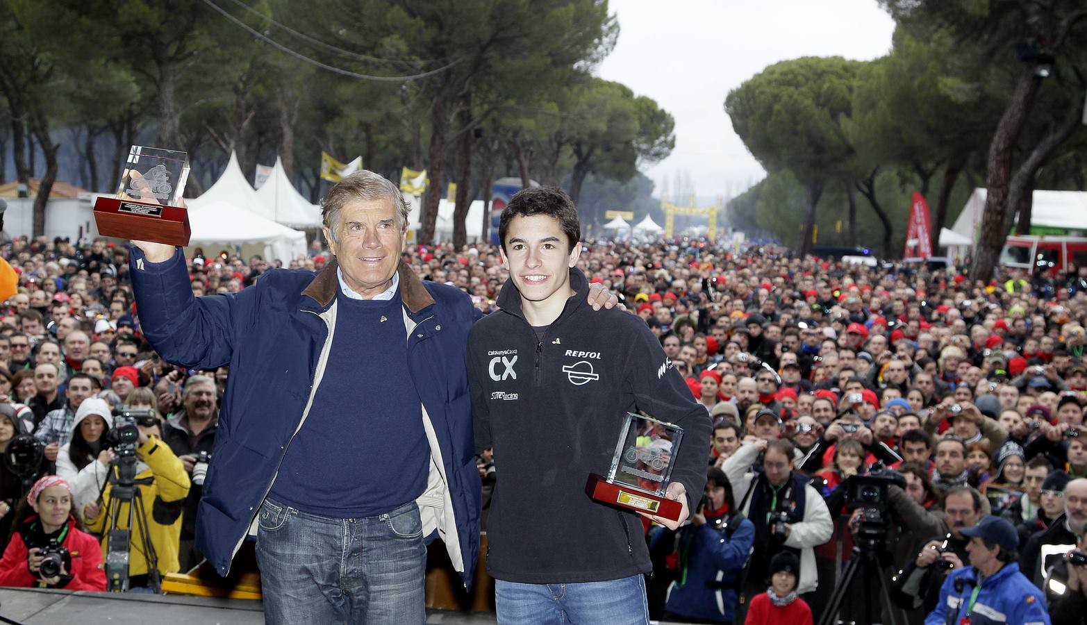 2011. Giacomo Agostini y Marc Márquez, con sus pinguinos de oro, ante una multitud que siguió la clausura de la concentración motera Pingüinos 2011.