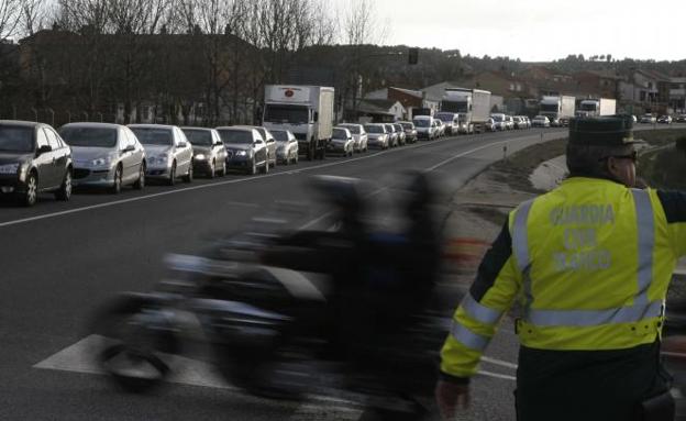 Dos agentes de la Guardia Civil regulan el tráfico al paso de un motorista de la concentración motera Pinguinos.