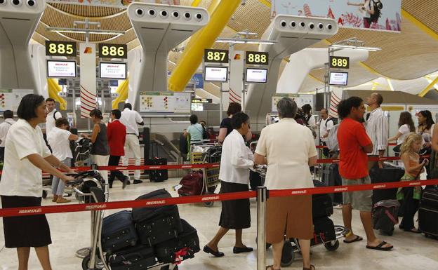 Pasajeros esperando con su equipaje en la T4 del aeropuerto de Barajas.