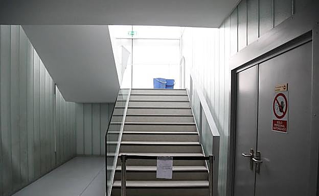 Cubos para recoger agua en una escalera clausurada por las goteras.