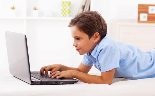 Un niño juega con un ordenador portátil. 