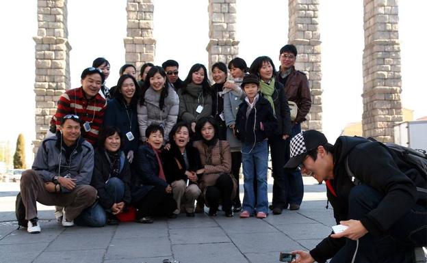 Turistas asiáticos se hacen fotos en la plaza del Azoguejo; a la izquierda. 