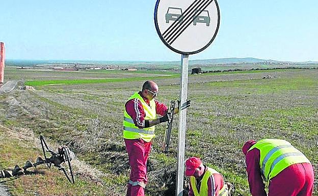 Tres trabajadores sustituyen una señal. 