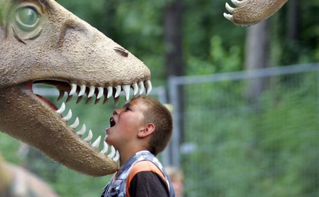Un niño metiendo su cabeza en la boca de la figura de un dinosaurio en Kleinwelka. 