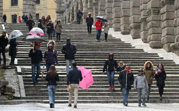 Turistas se protegen del mal tiempo durante el puente. 