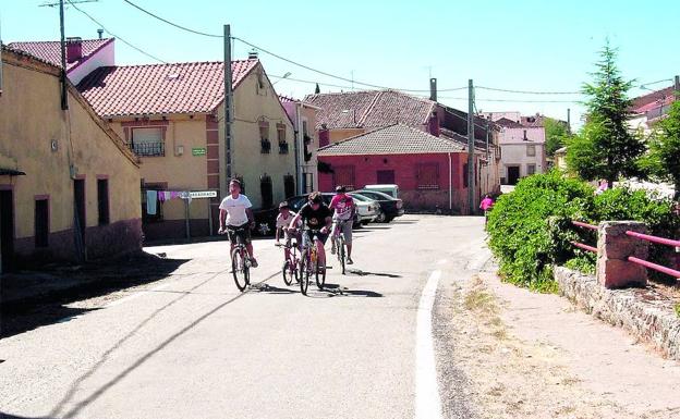 Unos niños montan el bicicleta por una calle de Aldeanueva de la Serrezuela. 