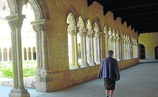 Una mujer camina por el claustro del monasterio. 