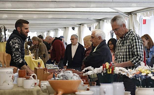 Un ceramista atiende a varios clientes durante la inauguración de la muestra. 