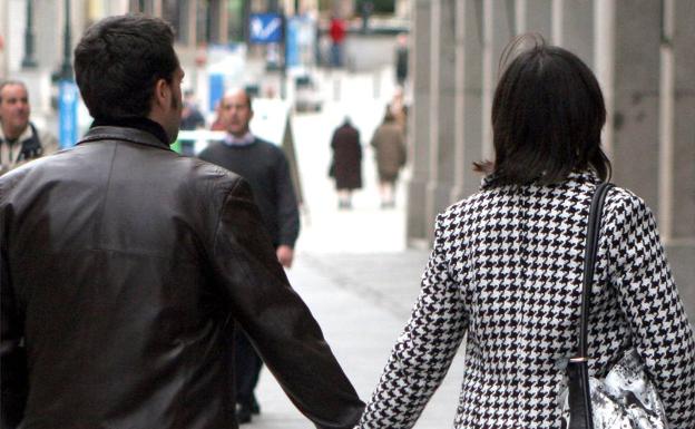 Una pareja pasea agarrada de la mano. 