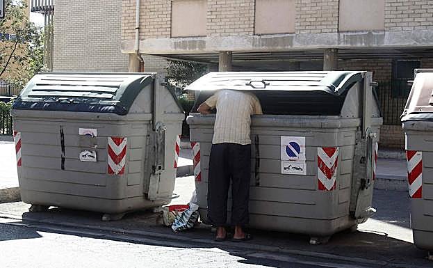 Una persona busca comida en un contenedor de basura del barrio vallisoletano de Huerta del Rey.