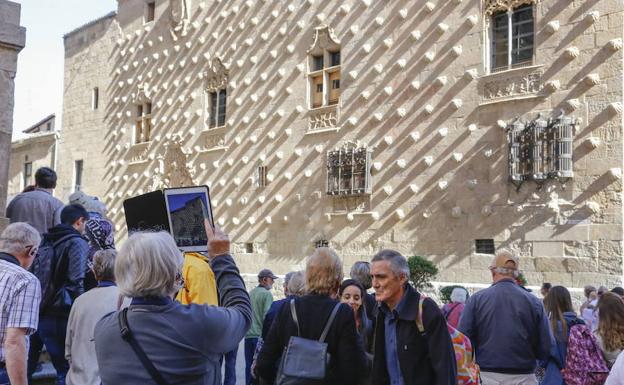 Un turista fotografía la Casa de las Conchas.