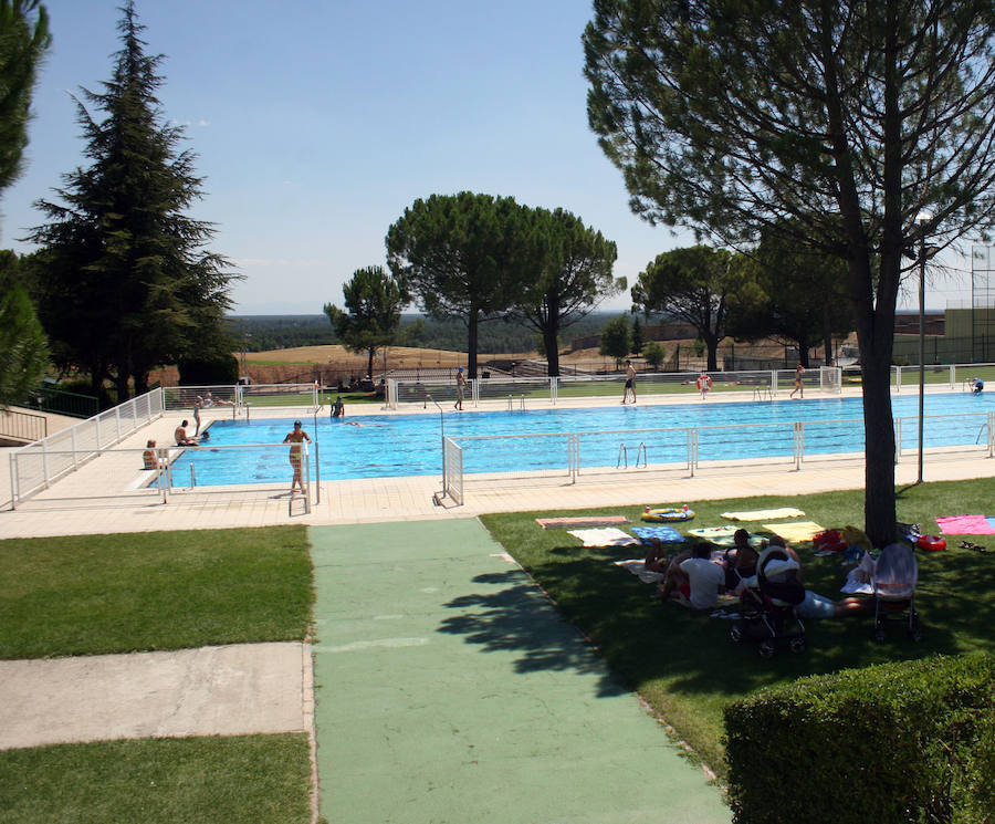 Bañistas y usuarios a la sombra en la piscina de verano de Cuéllar.