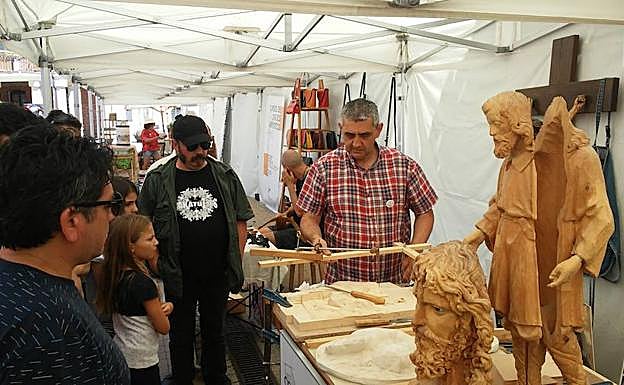 Un grupo de visitantes observa uno de los expositores artesanales de la feria. 