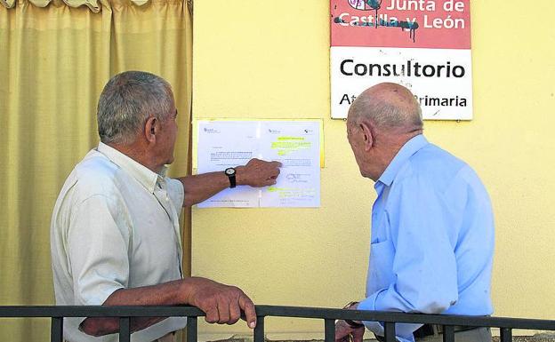 Dos vecinos leen el aviso de los servicios mínimos en el consultorio de Villalazán (Zamora). :: 