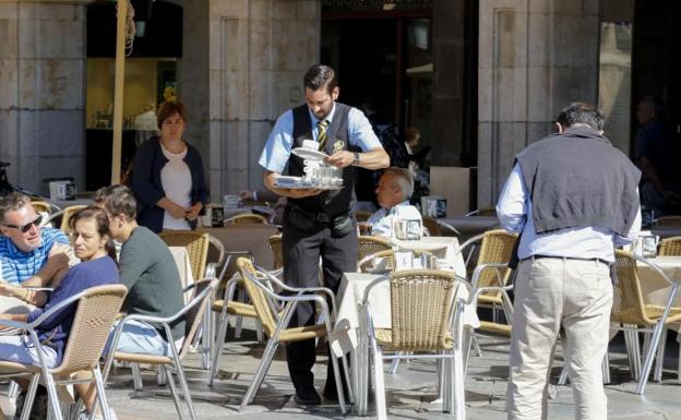 Un camarero, de los puestos con mayor creación de empleo, sirve una consumición en la Plaza Mayor de Salamanca.
