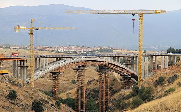 Dos grúas trabajan en la construcción del viaducto sobre el río Eresma. 