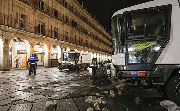 Los vehículos encargados de la limpieza de la ciudad retiran los desperdicios esparcidos por la Plaza Mayor tras la multitudinaria celebración de la Nochevieja Universitaria. 