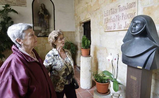 Dos mujeres contemplan un busto de Santa Teresa en el interior de la casa de ésta.